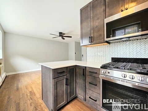 A kitchen with dark wood cabinets and a stainless steel oven.