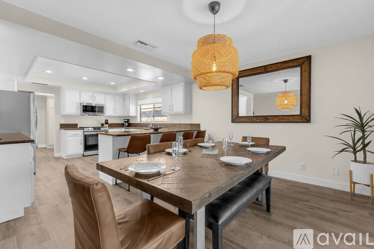 A dining room with a wooden table set for two with a mirror above it.