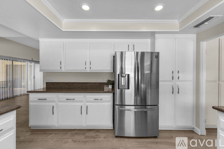 A kitchen with white cabinets and a stainless steel refrigerator.