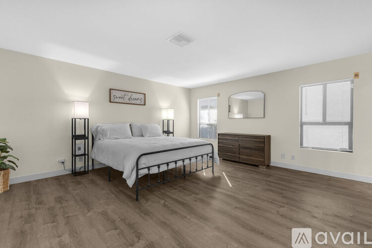 A bedroom with a bed, nightstand, and a mirror on the wall.