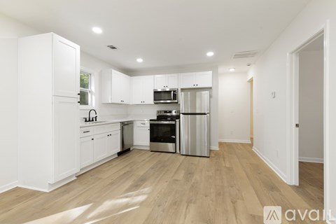A kitchen with white cabinets and wooden floors.