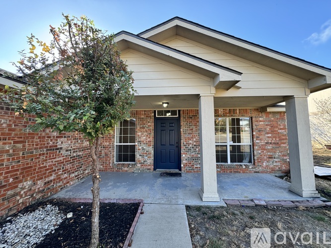 A house with a blue door and a tree in front.