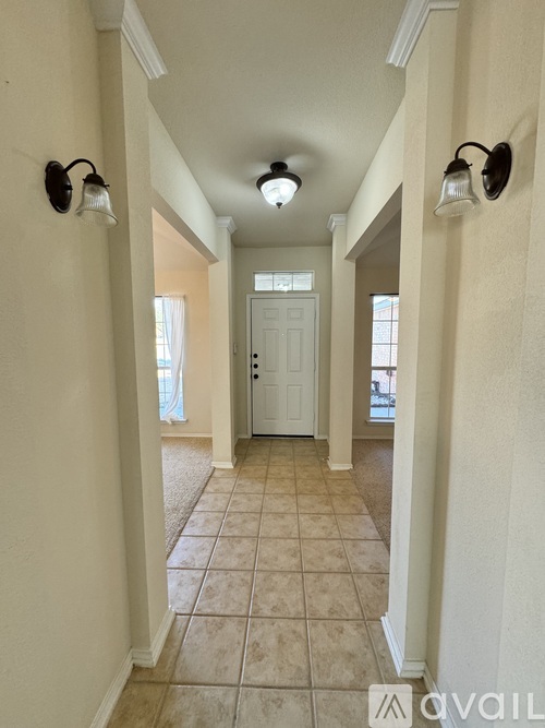 A hallway with a white door and two lights on the wall.