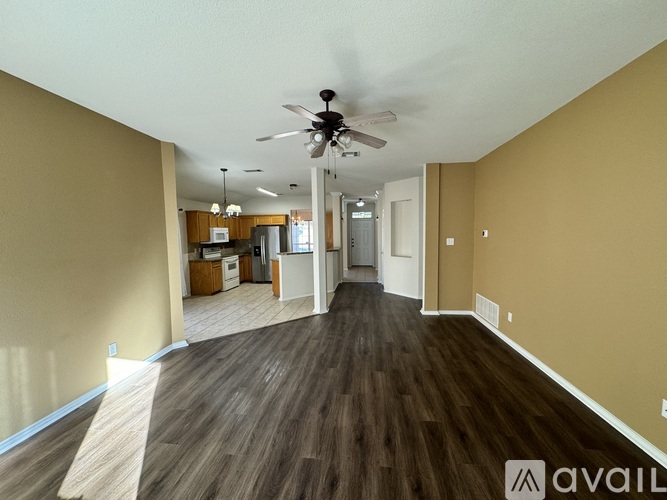 A spacious room with a ceiling fan and wooden flooring.