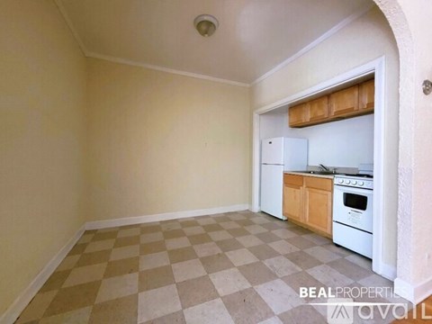 A kitchen with white appliances and wooden cabinets is available for rent.