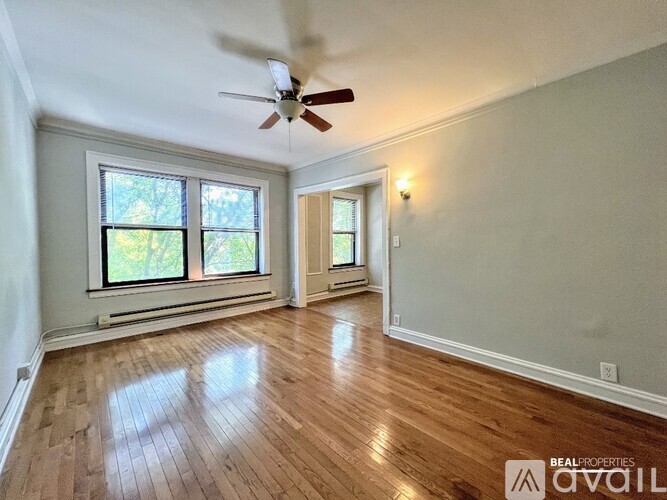 A room with a ceiling fan and two windows.