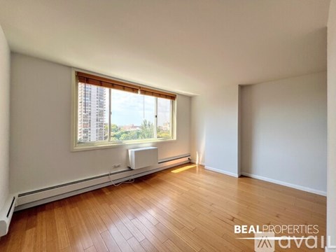 A room with wooden floors and a window showing a city view.