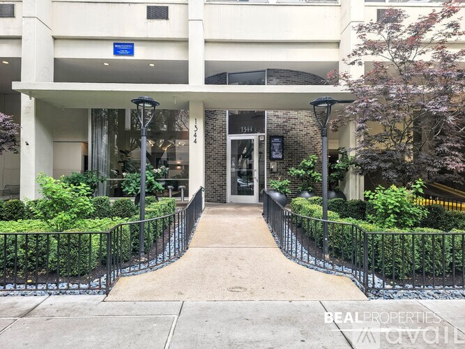The entrance to a building with a black fence and bushes on either side.