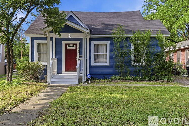 A blue house with a red door and a white porch.
