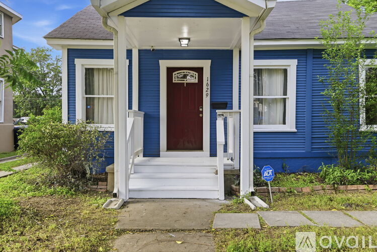 A blue house with a red door and white steps leading to the entrance.