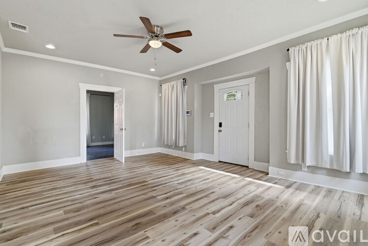 A spacious room with wooden flooring and a ceiling fan.
