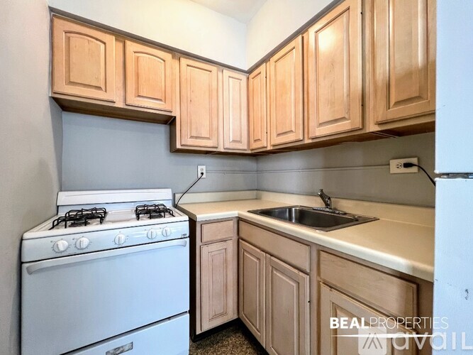 A kitchen with a white stove and wooden cabinets.