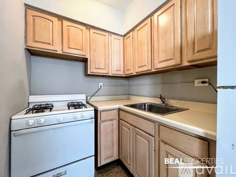 A kitchen with a white stove and wooden cabinets.