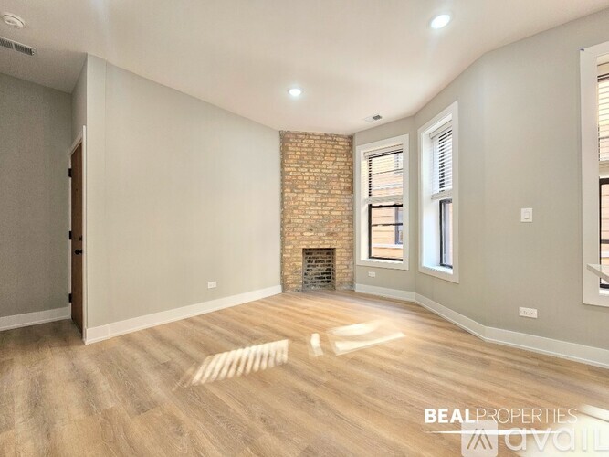 A spacious room with a brick fireplace and wooden flooring.