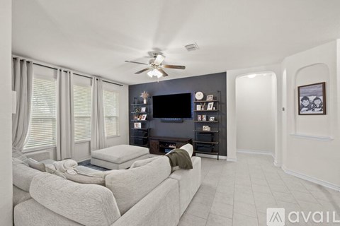 A living room with a white couch and a ceiling fan.