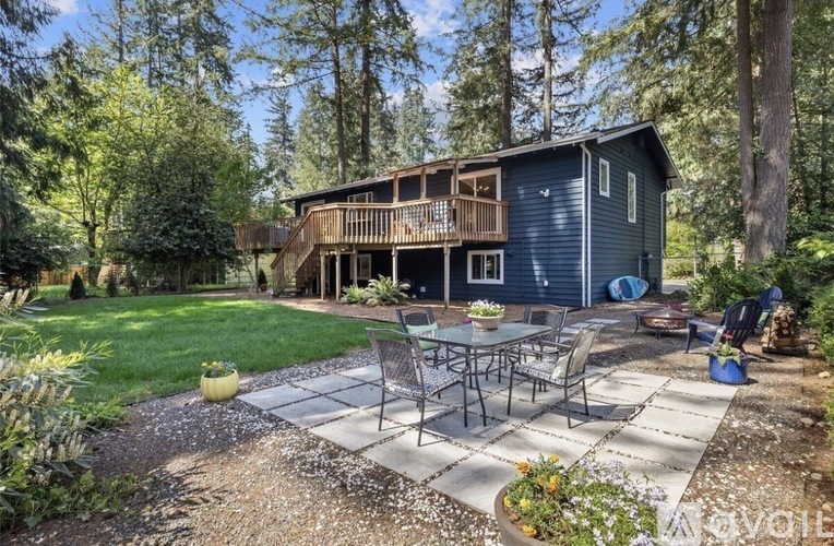 A house with a deck and a patio surrounded by trees.