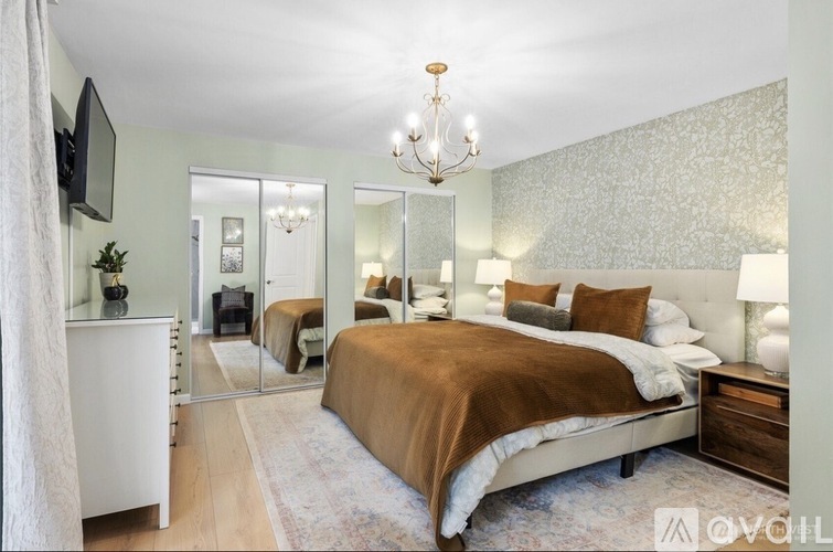 A bedroom with a large bed, a chandelier, and a television.