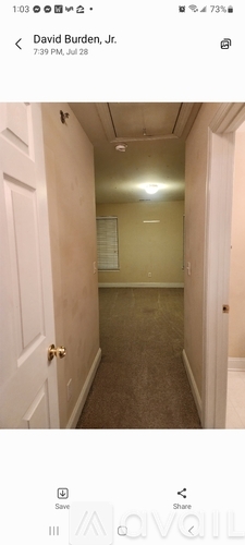 A long, narrow hallway with a door on the left and a bulletin board on the wall.