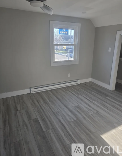 A room with a window and a wooden floor.