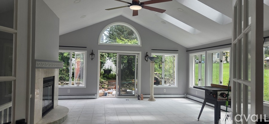 A large, empty room with a fireplace and a ceiling fan.