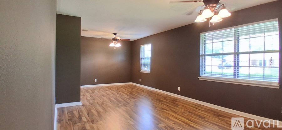 A room with wooden floors and a window with blinds.