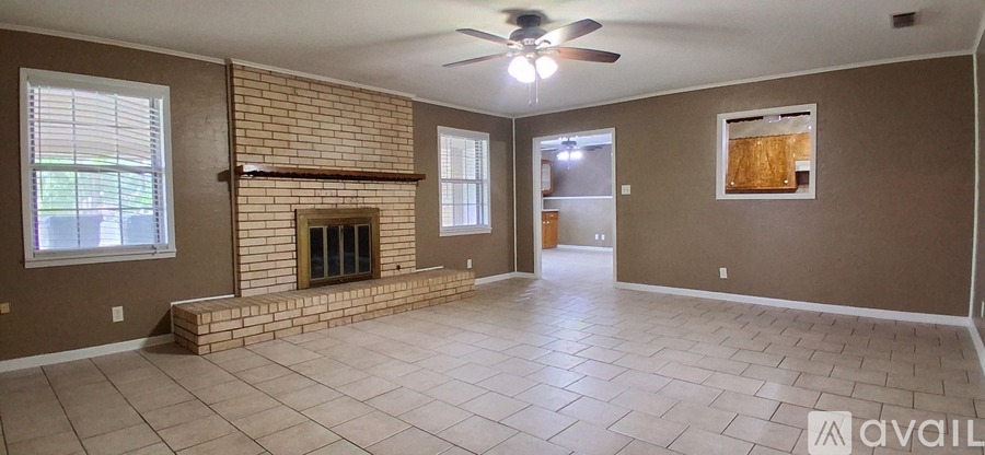 A living room with a brick fireplace and a ceiling fan.