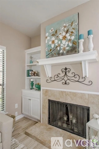 A white fireplace with a painting above it and a shelf with decorative items.