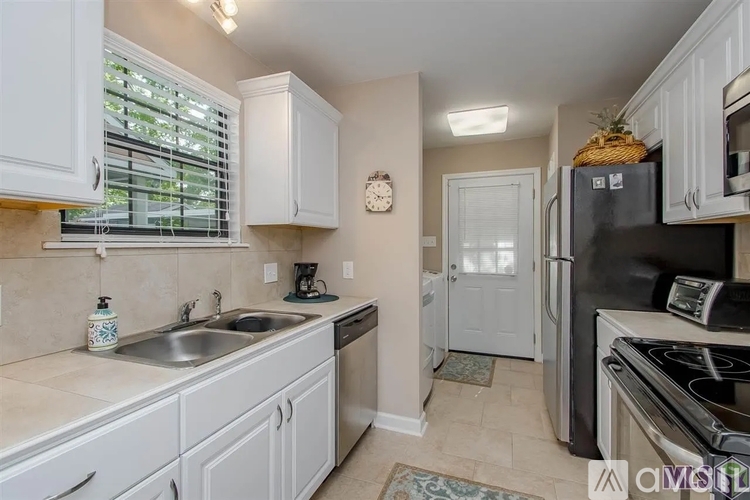 A kitchen with white cabinets and a black refrigerator.