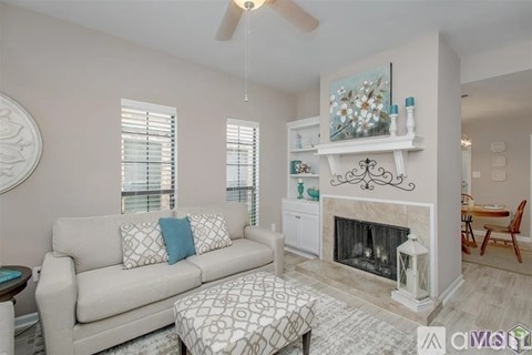 A living room with a couch, a fireplace, and a painting on the wall.
