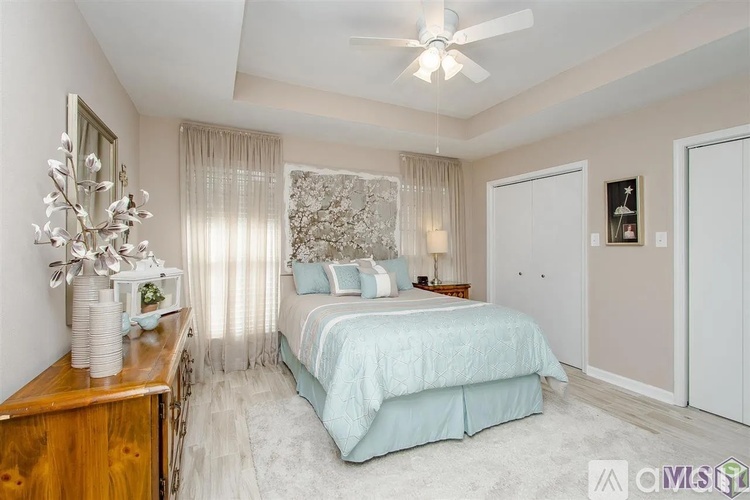 A bedroom with a bed, a dresser, and a ceiling fan.