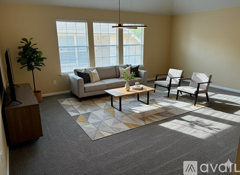 A living room with a grey carpet and a grey couch.