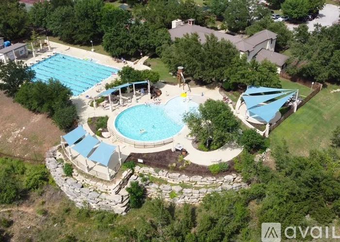 An aerial view of a swimming pool surrounded by trees and a stone wall.