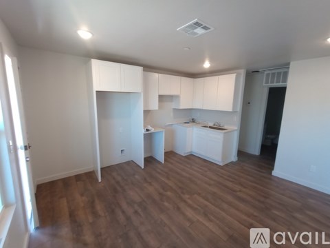A spacious kitchen with white cabinets and a wooden floor.