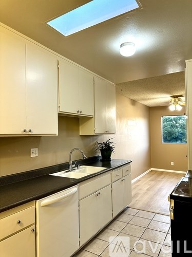 A kitchen with white cabinets and black countertops.