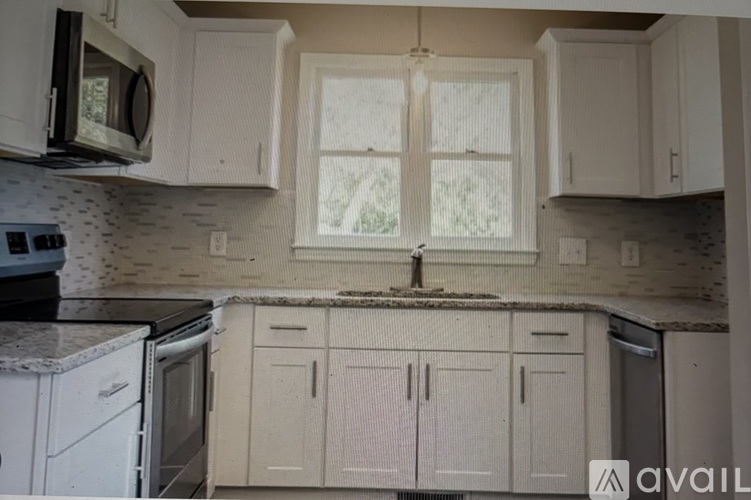 A kitchen with white cabinets and appliances is available for rent.