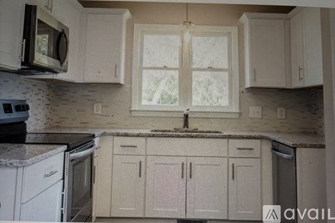 A kitchen with white cabinets and appliances is available for rent.