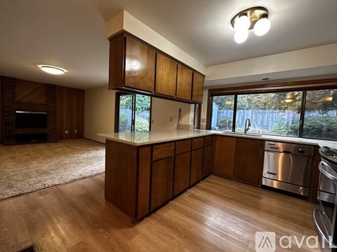 A kitchen with wooden cabinets and a large window.