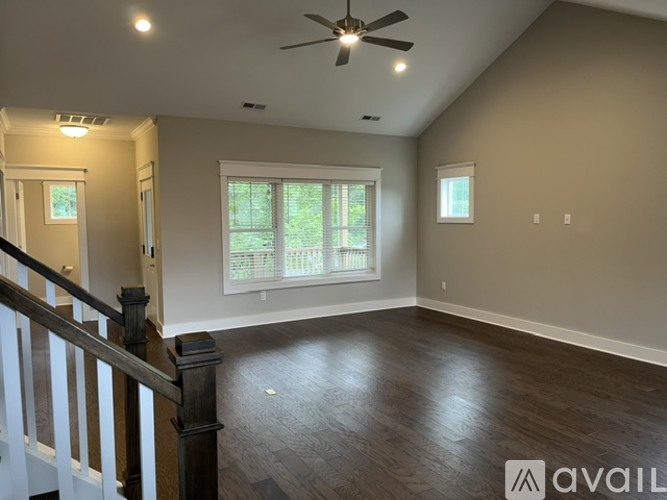 A spacious room with a ceiling fan and a window with blinds.