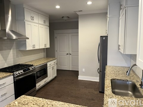A kitchen with white cabinets and a granite countertop.