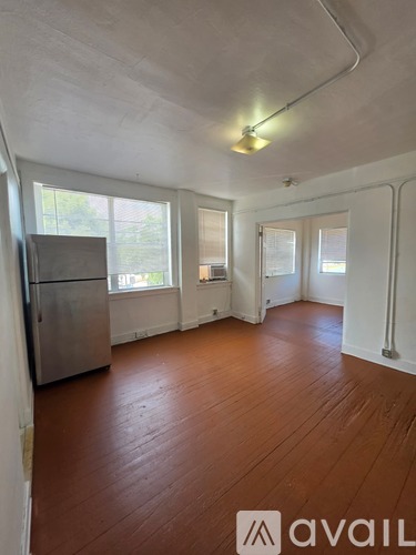 A room with wooden floors and a refrigerator.