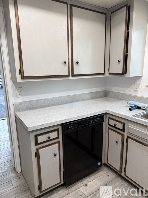 A kitchen with white cabinets and a black dishwasher.