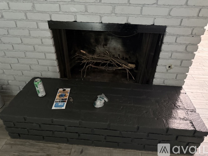A fireplace with a black mantle and a white brick wall.
