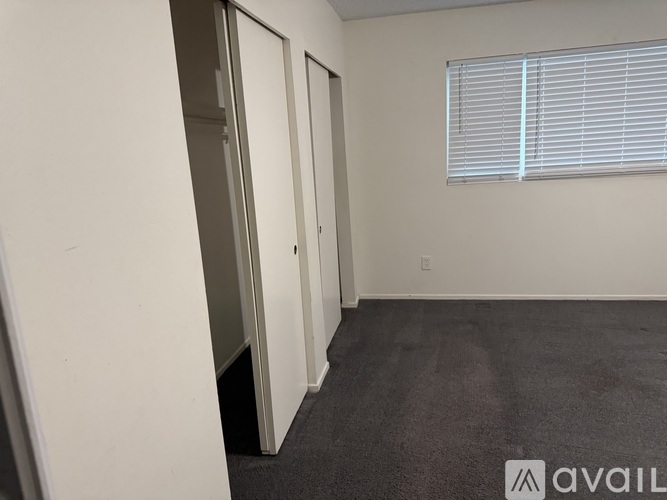 A room with a carpeted floor and a window with blinds.