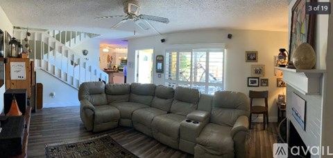 A living room with a grey sectional sofa and a fan.