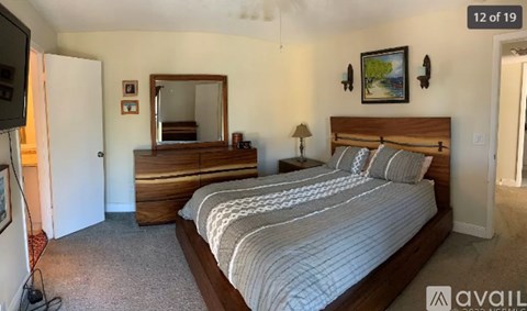 A bedroom with a large bed and a dresser with a mirror above it.