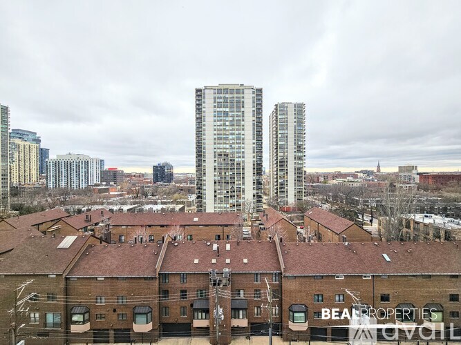 A view of a cityscape with a large building in the center and several smaller buildings in the foreground.