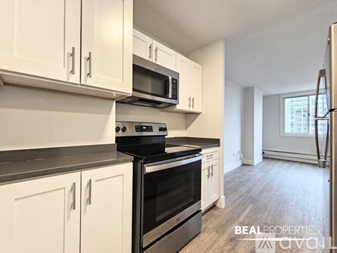A kitchen with white cabinets and black countertops.