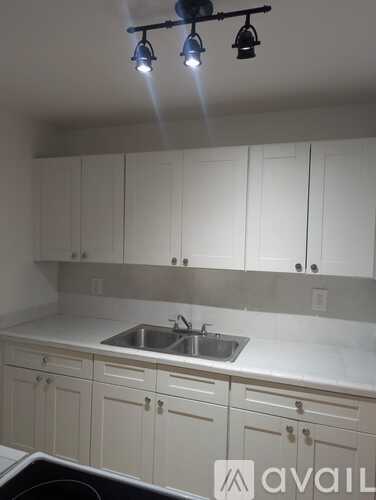 A kitchen with white cabinets and a sink under a faucet.