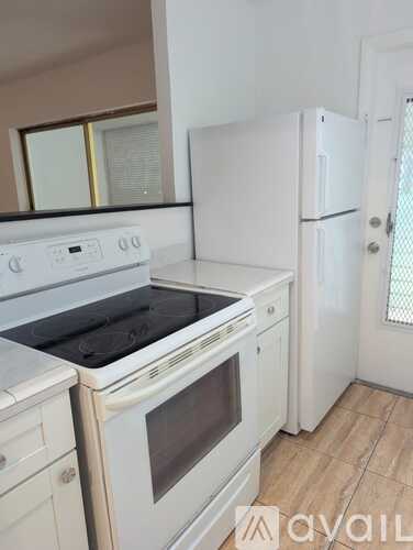 A white kitchen with a stove, oven, and refrigerator.