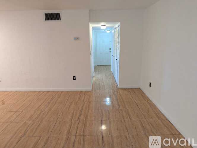 A room with wooden flooring and a doorway leading to another room.